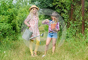 Rustic children nature background. Agriculture concept. Girls in hats planting plants. Sisters helping at farm. Family