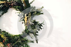 Rustic christmas wreath made of pine branches, cones and berries closeup  on white wall. Stylish christmas wreath. Scandinavian