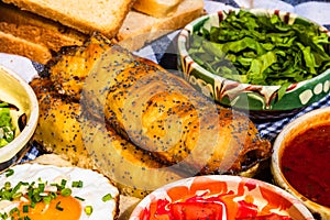 Rustic composition with sausages rolls, fried egg on toast bread, different bowls with sauce and chopped vegetables