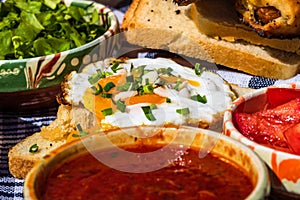 Rustic composition with sausages rolls, fried egg on toast bread, different bowls with sauce and chopped vegetables