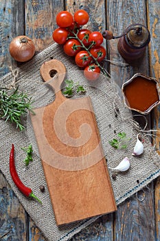 Rustic composition with wooden board, pepper mill, tomato souce, fresh herbs, vegetables and spices. Country style. Baking or cook