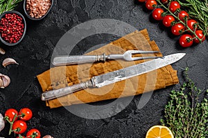 Rustic Cutting Board and meat fork on Dark wooden board. Black background. Top view. Copy space