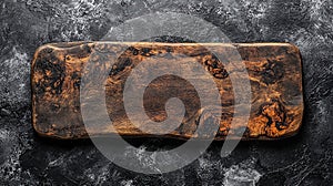 Rustic dark brown wooden rectangular cutting board on a dark gray textured surface