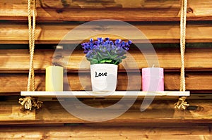 Rustic decor, natural wood wall, handmade wooden shelf on ropes with flowers and candles