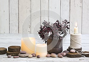 Rustic decoraton with candles, old reel and elderberries in a vase on a white wooden background photo