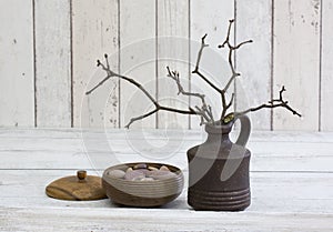 Rustic decoraton with round wooden box and twigs in a vase on a white wooden background photo