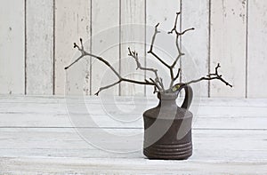 Rustic decoraton with twigs in a vase on a white wooden background photo