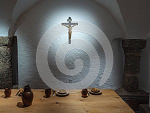 Rustic Dining Table with Crucifix on Stone Wall