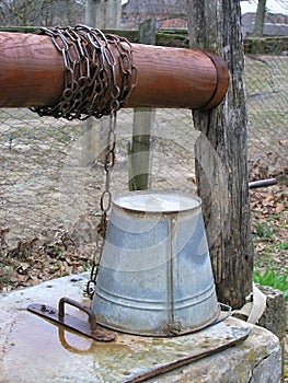 Rustic draw well with metal bucket on a chain. Authentic Russian countryside life