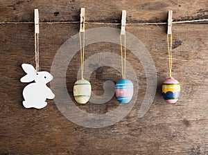 Rustic Easter background: Vintage painted eggs and white heart hang on clothespins against old wooden wall. Holiday concept