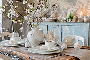 rustic Easter table setting with painted eggs, painted dishes and flowering branches in the bright dining room, the concept of