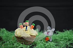 Cupcake topped with a miniature person figurine holding a sign board indicating I love Easter with some decorations