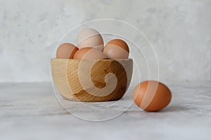 Rustic eggs in a wooden plate, one egg next to the plate