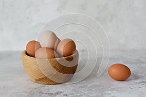 Rustic eggs in a wooden plate, one egg next to the plate