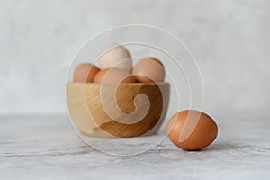 Rustic eggs in a wooden plate, one egg next to the plate