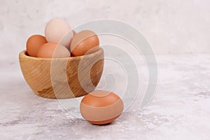 Rustic eggs in a wooden plate, one egg next to the plate