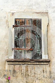 Rustic faded vintage wooden window shutter set in a stone wall
