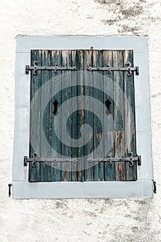 Rustic faded vintage wooden window shutter set in a stone wall