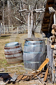 Rustic farmyard scene with two old barrels and a woodpile