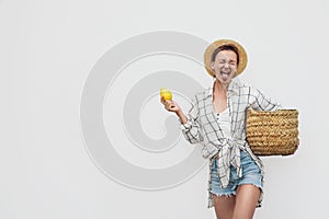 Rustic fashion woman holding basket of fresh lemons against white wall. Local food market and organic produce. Zero waste