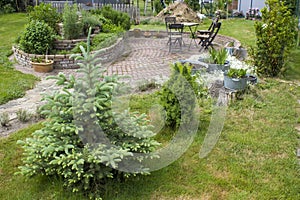 Rustic garden -  spruce,  plants in tin tub, herb spiral, chairs and table