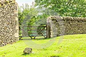 Rustic gate in drystone wall in Bibury England UK.