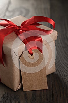 Rustic gift box with red ribbon bow and empty tag