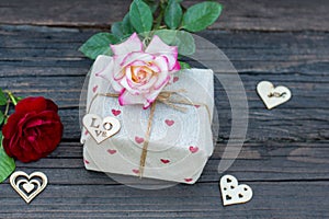 Rustic gift box with roses and hearts, on old wood table.