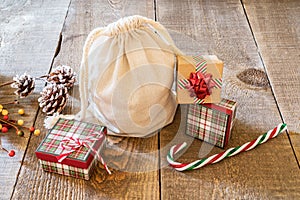 Rustic gift sack with candy canes and pine cones on wooden surface