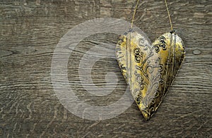 Rustic golden heart ornament on vintage wooden background