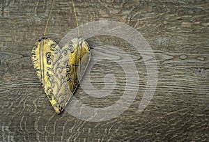 Rustic golden heart ornament on vintage wooden background