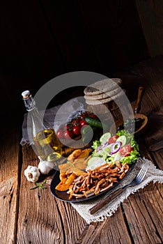 A Rustic gyros plate it green salad and potato wedges