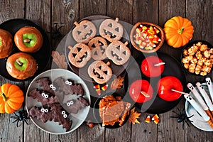 Rustic Halloween treat table scene, top view over a dark wood background