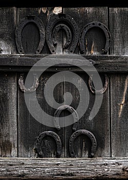 Rustic horseshoe on vintage wooden background. Old horse shoe hanging on wooden door in the village - symbol of luck