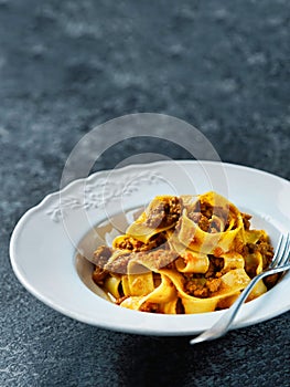 Rustic italian pappardelle bolognese pasta in meat sauce