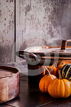 Rustic kitchen scene with copper cookware and pumpkins.