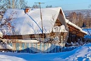 Rustic log house covered with snow. Village Visim, Sverdlovsk region, Russia.