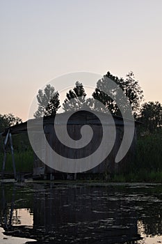 Rustic look of a old house made of tin with sunset sky background in the middle of Dal lake, Srinagar, Jammu and Kashmir, India