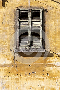 Rustic louvred window shutters and yellow wall
