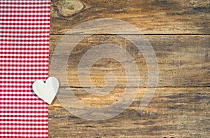 Rustic love background, wooden heart on red checkered fabric.
