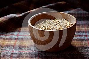 Rustic malted barley grains in wooden bowl