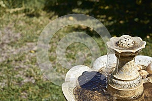 Rustic marble ornamental fountain with flowing and cascading water located in a garden