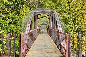 Rustic Metal Truss Bridge in Lush Park with Autumn Foliage, Eye-Level View