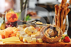 Rustic mix of cheese cuts, mushrooms and fruits on a wooden platter, during brunch buffet. Tasty assortment of fresh cheese