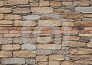 Rustic natural stones wall with two rows of bricks in the middle.