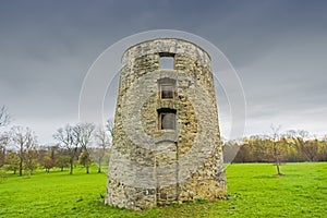 Rustic old brick silo ruin stands tall against a stormy blue sky