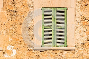 Rustic old green window shutter with vintage stone wall