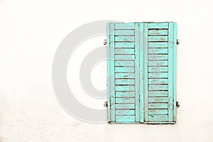 Rustic old grungy and weathered green cyan wooden closed window shutters with peeling paint