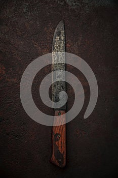 Rustic old kitchen knife with decayed carbon steel blade on rusty background