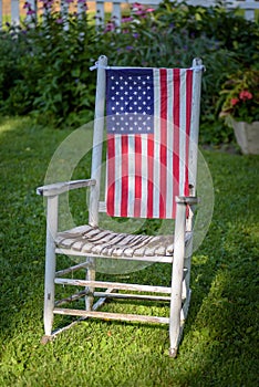 Rustic old white painted rocking chair sitting in lawn decorated